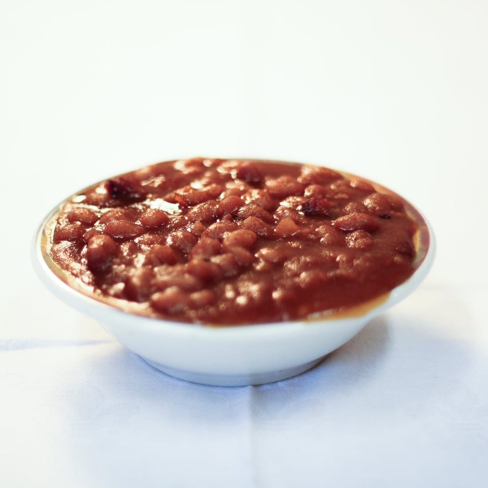 A white bowl filled with Parks Old Style Bar-B-Q baked beans on a white tablecloth.